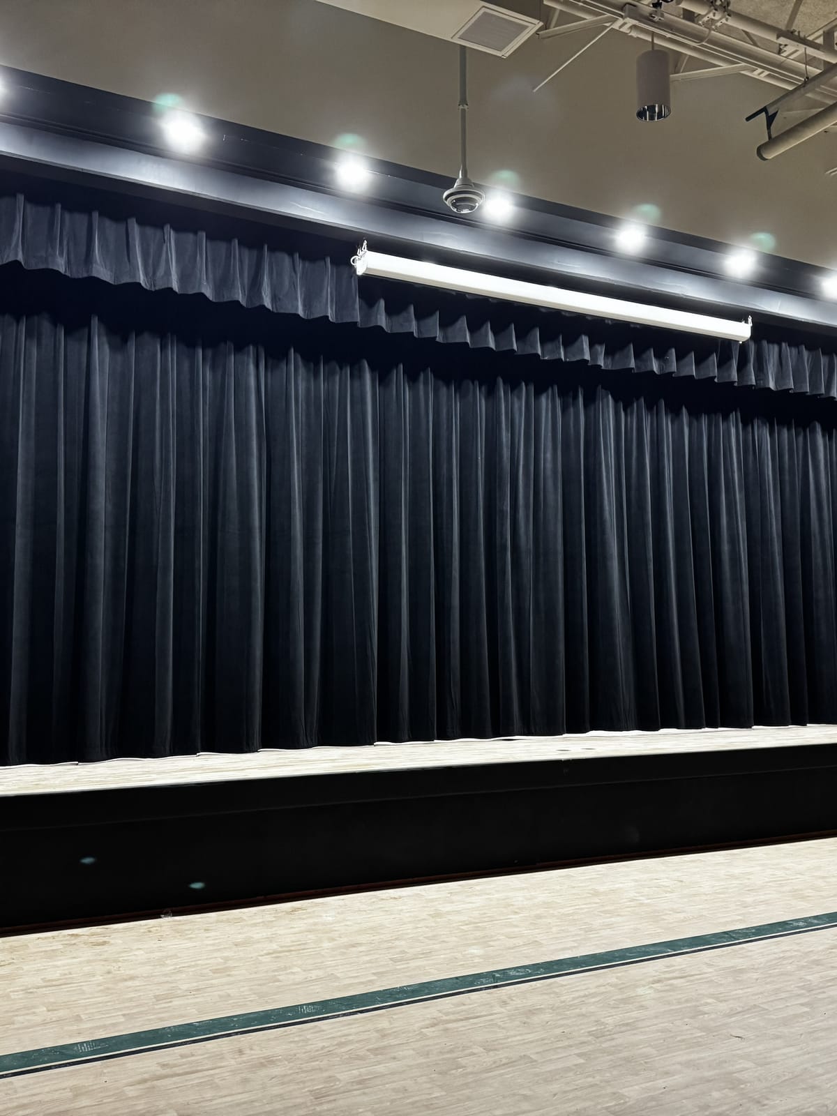 Black velour stage curtain with matching valance framing a school auditorium stage