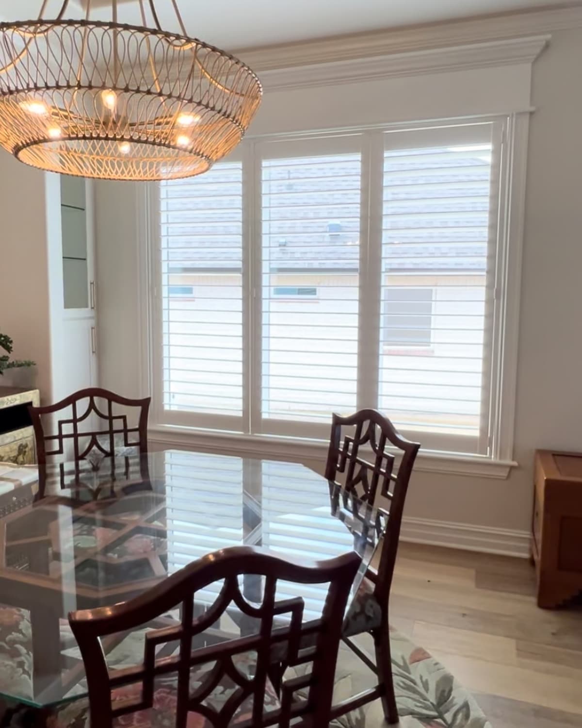 White plantation shutters in elegant dining room with chandelier and glass table